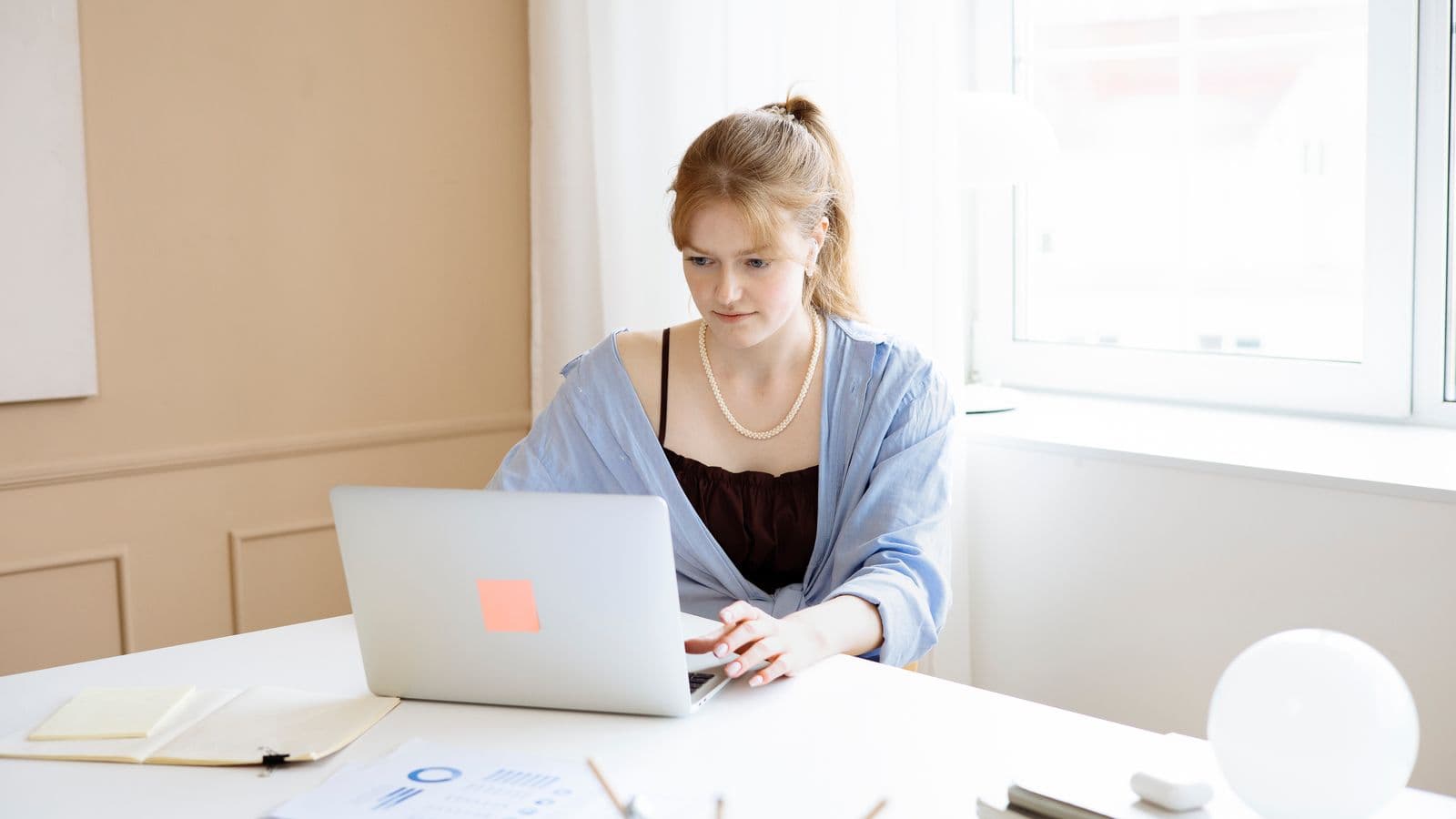 Tânără profesionistă care lucrează cu documente digitale la laptop
