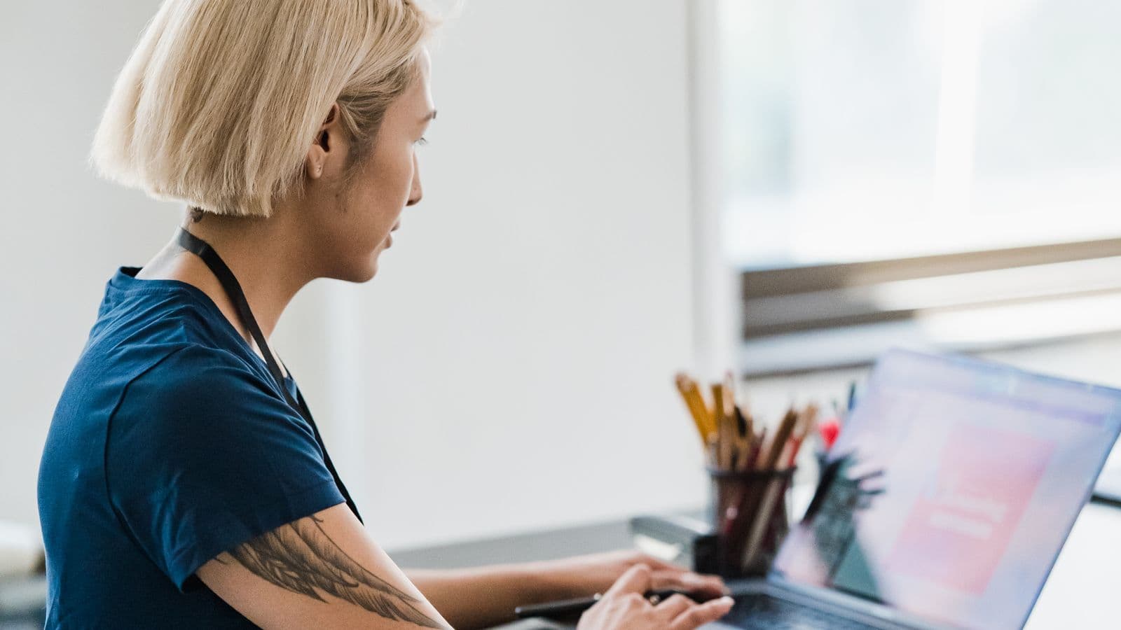 Tânără profesionistă care lucrează la laptop într-un birou luminos