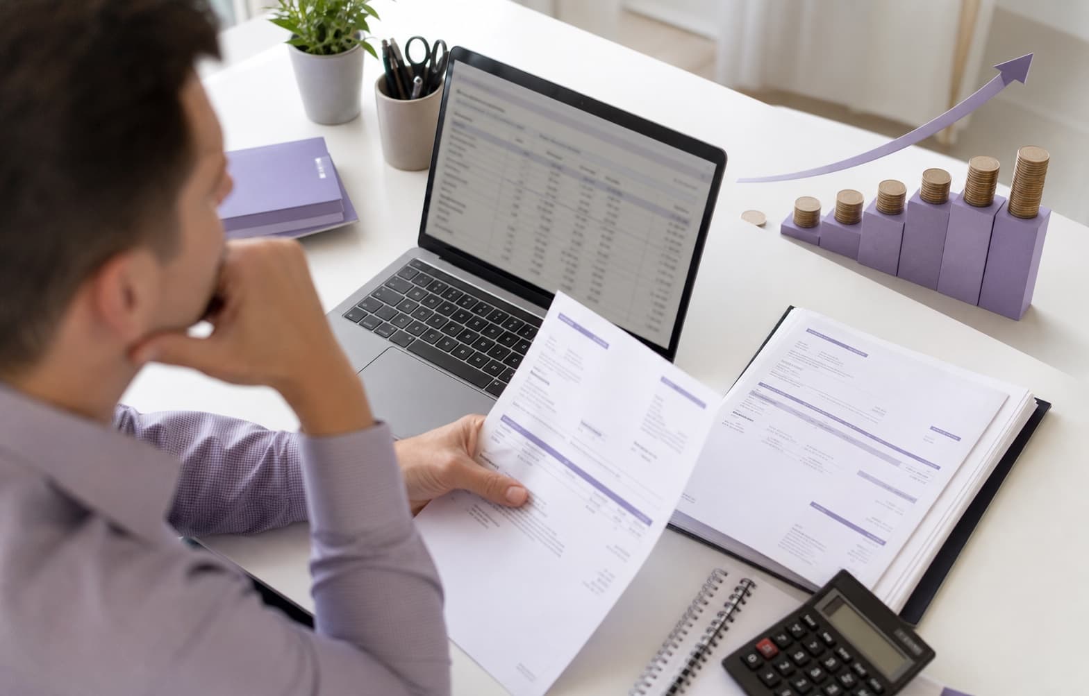 Manager care urmărește facturile și fluxul de numerar pe laptop
